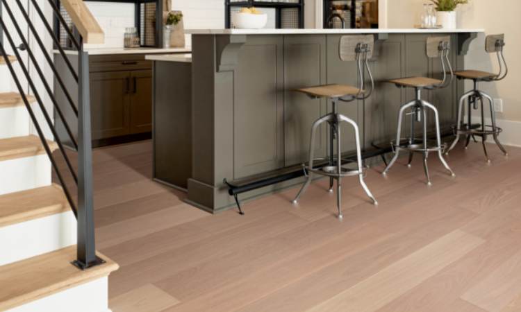 warm toned hardwood flooring in kitchen with grey counters and barstools